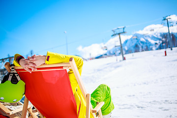 Image showing Women at mountains in winter lies on sun-lounger