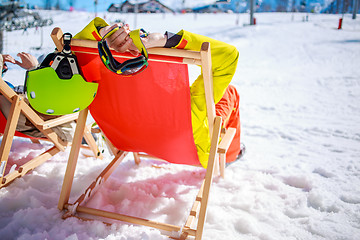 Image showing Women at mountains in winter lies on sun-lounger