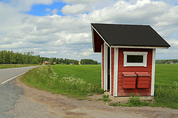 Image showing Landscape of Red Wooden Bus Stop Shelter with Two Mail Boxes