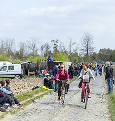 Image showing Two Casual Women Cycling on a Cobblestoned Road