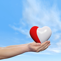 Image showing Conceptual human hand with heart and blue sky