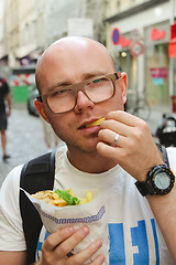 Image showing portrait of bald man eating at street