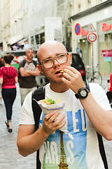 Image showing portrait of bald man eating at street