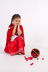 Image showing The little girl spilled cherries is sad