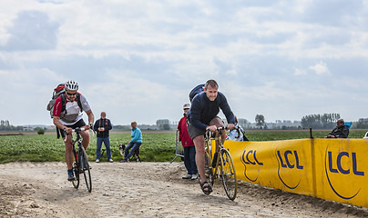 Image showing Amateur Cyclists Riding on a Cobblestoned Road