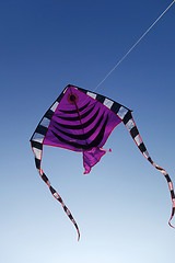 Image showing Colorful kite flying up in blue sky