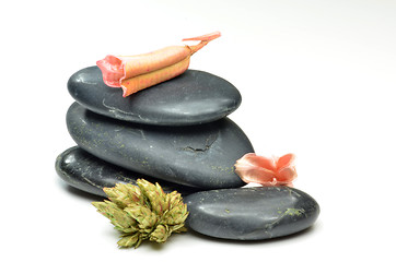 Image showing Stack of black stones with fake flowers