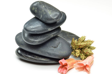 Image showing Stack of black stones with fake flowers