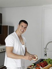 Image showing man cooking at home preparing salad in kitchen