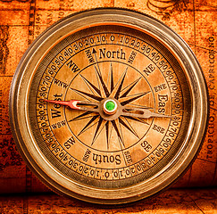 Image showing Vintage compass lies on an ancient world map.