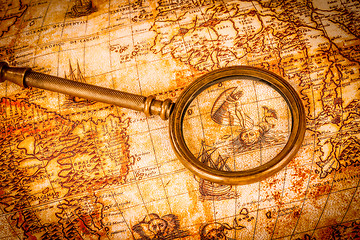 Image showing Vintage magnifying glass lies on an ancient world map