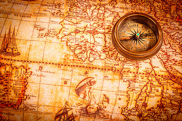 Image showing Vintage compass lies on an ancient world map.