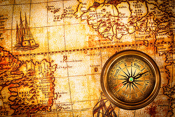 Image showing Vintage compass lies on an ancient world map.