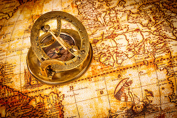 Image showing Vintage compass lies on an ancient world map.