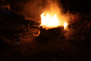 Image showing Squad of Four Firefighters Dousing a Burning Shed