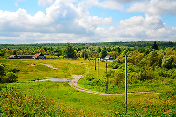 Image showing Rural landscape with dirt road, houses and power poles in the sp