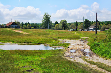 Image showing Rural landscape with dirt road, houses and power poles in the sp