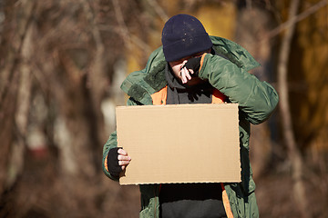 Image showing Homeless man holds blank cardboard for your own text