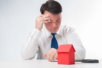 Image showing Sad Man with a magnifying glass and paper house