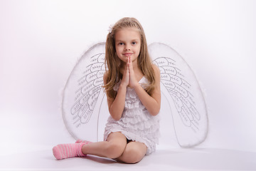 Image showing Sitting girl in an angel costume with folded hands