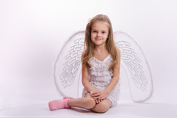 Image showing Sitting girl in an angel costume on a white background