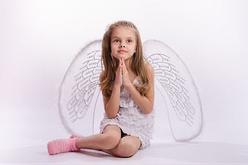 Image showing Seated girl with angel wings folded hands