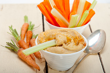 Image showing fresh hummus dip with raw carrot and celery 