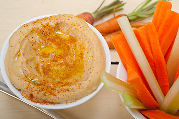 Image showing fresh hummus dip with raw carrot and celery 