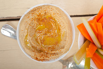 Image showing fresh hummus dip with raw carrot and celery 