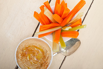 Image showing fresh hummus dip with raw carrot and celery 