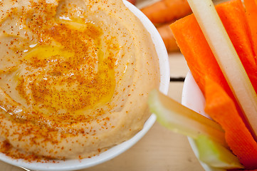 Image showing fresh hummus dip with raw carrot and celery 