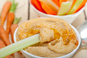 Image showing fresh hummus dip with raw carrot and celery 