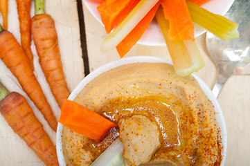 Image showing fresh hummus dip with raw carrot and celery 