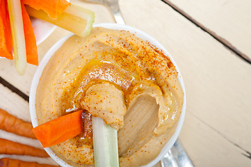 Image showing fresh hummus dip with raw carrot and celery 