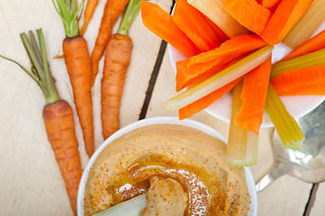 Image showing fresh hummus dip with raw carrot and celery 