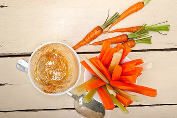 Image showing fresh hummus dip with raw carrot and celery 