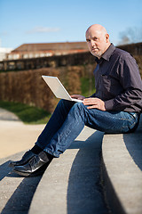 Image showing Man sitting on a bench using a laptop