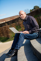 Image showing Man sitting on a bench using a laptop