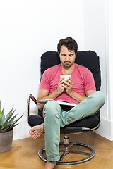 Image showing Man Sitting on Chair with Book and a Drink