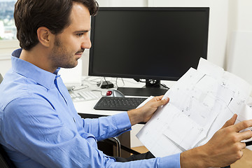 Image showing Young man reading written agreements for work