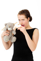 Image showing attractive smiling brunette holding teddy bear grimacing with pe