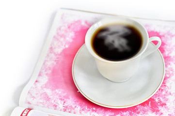 Image showing A cup of hot coffee and a magazine
