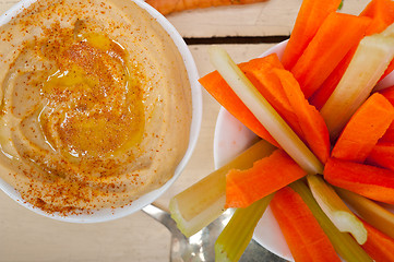 Image showing fresh hummus dip with raw carrot and celery 