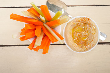 Image showing fresh hummus dip with raw carrot and celery 