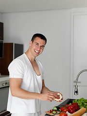 Image showing man cooking at home preparing salad in kitchen