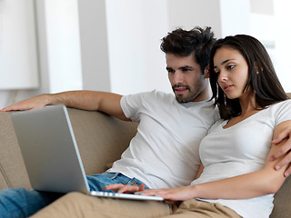 Image showing relaxed young couple working on laptop computer at home