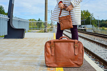 Image showing Womans hands holding bag and suitcase at station