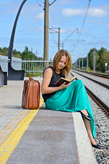 Image showing Young girl sitting on the station and reading