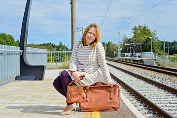 Image showing Woman sitting with brown bag and suitcase 