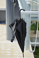 Image showing Black umbrella hanging on the railing outside